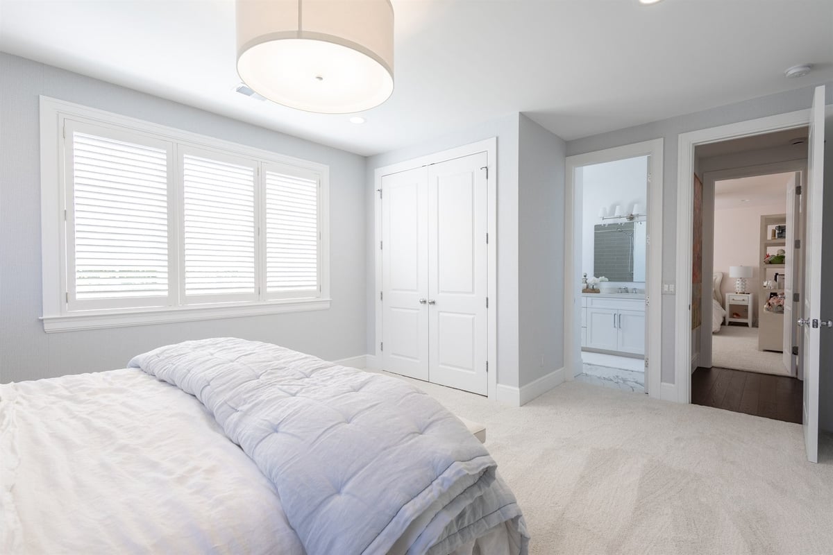 bedroom-with-white-closet-doors-an-ensuite-bath-and-shutters-southeast-mi-optimized