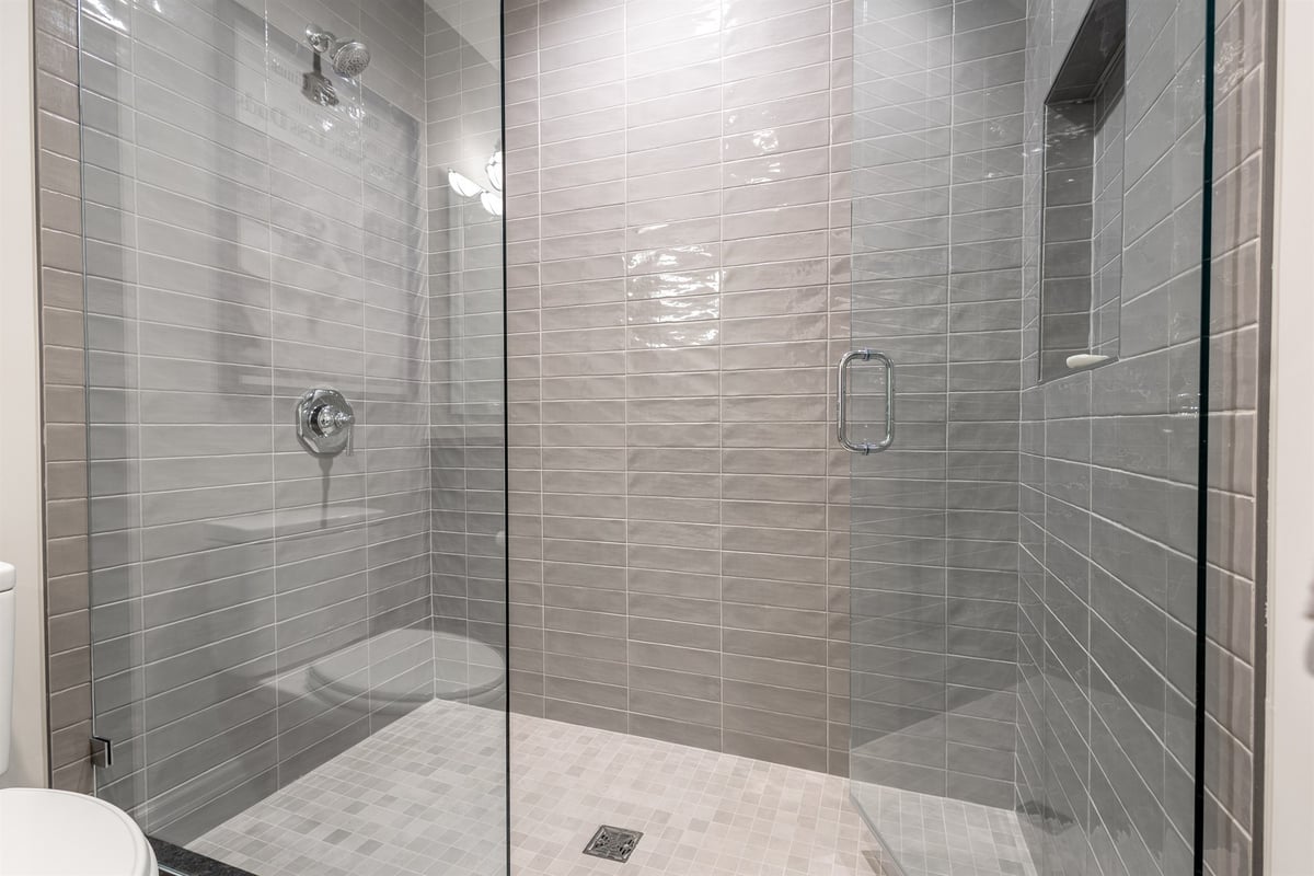 gray-tiled-walk-in-shower-with-a-glass-door-and-bench-southeast-mi-optimized