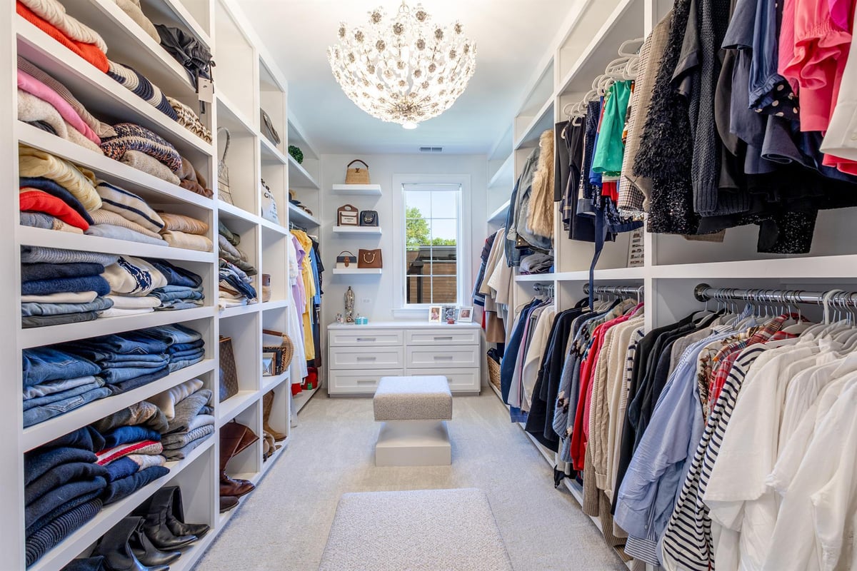 large-walk-in-closet-with-white-built-in-shelving-and-a-chandelier-southeast-mi-optimized