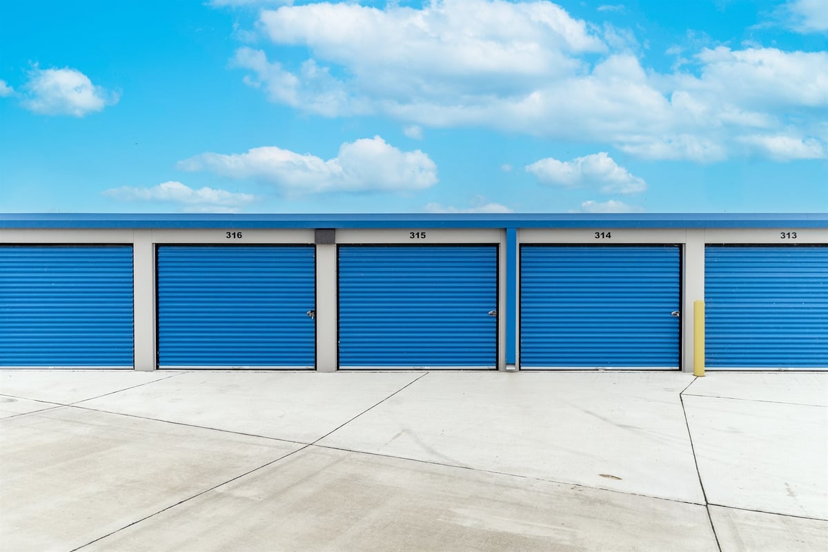 blue-roll-up-doors-lining-a-clean-concrete-drive-commercial-self-storage-southeast-mi-optimized