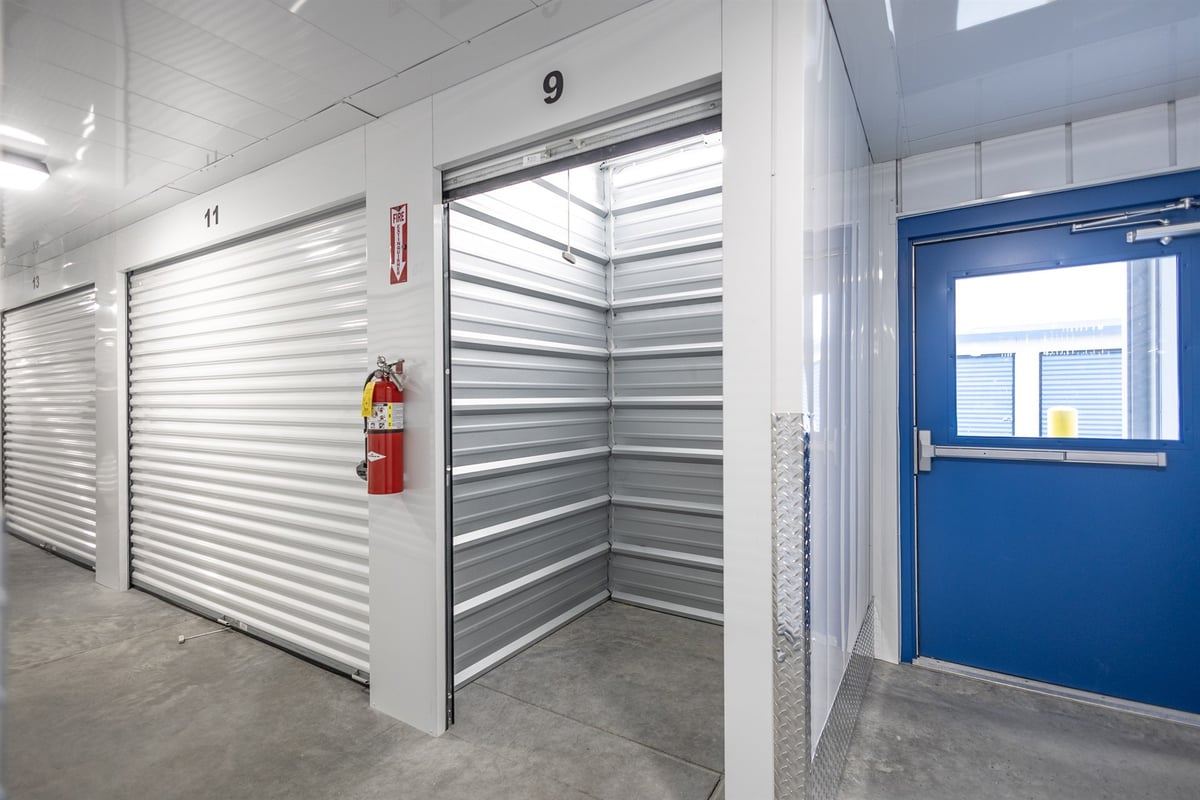 interior-hallway-with-an-open-unit-and-a-blue-exit-door-commercial-self-storage-southeast-mi-optimized