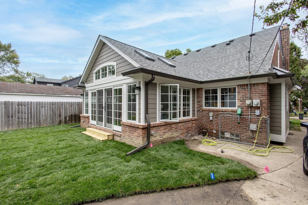 rear-sunroom-addition-exterior-with-a-wall-of-windows-and-brick-base-southeast-mi-optimized