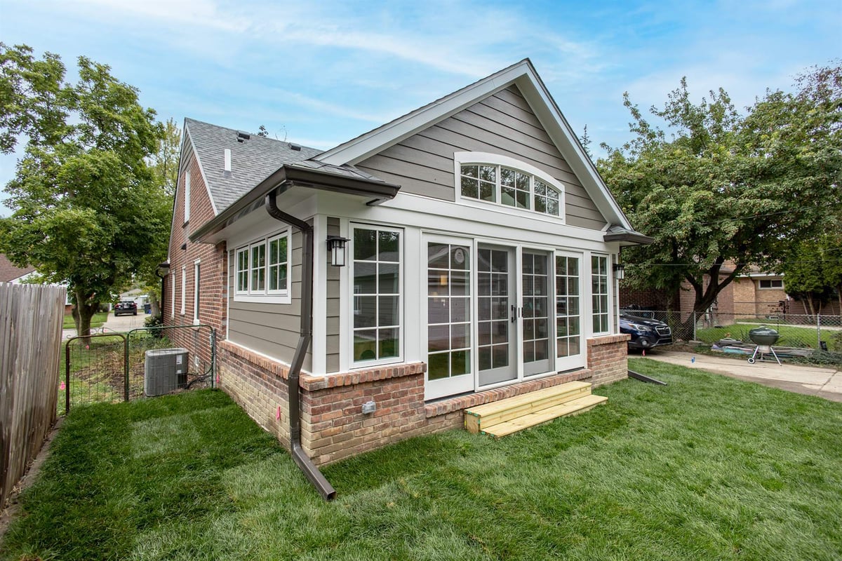rear-sunroom-addition-with-a-wall-of-windows-and-a-brick-base-southeast-mi-optimized