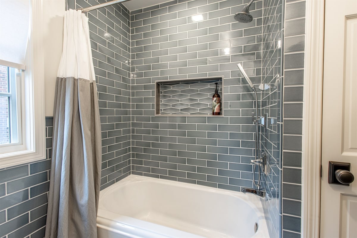 tub-shower-with-blue-subway-tile-a-niche-and-a-window-southeast-mi-optimized