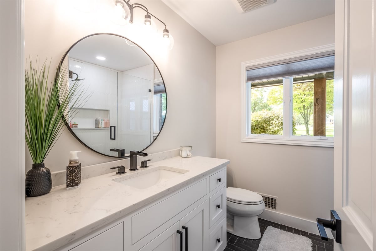bathroom-vanity-with-a-marble-top-and-a-round-black-framed-mirror-southeast-mi-optimized