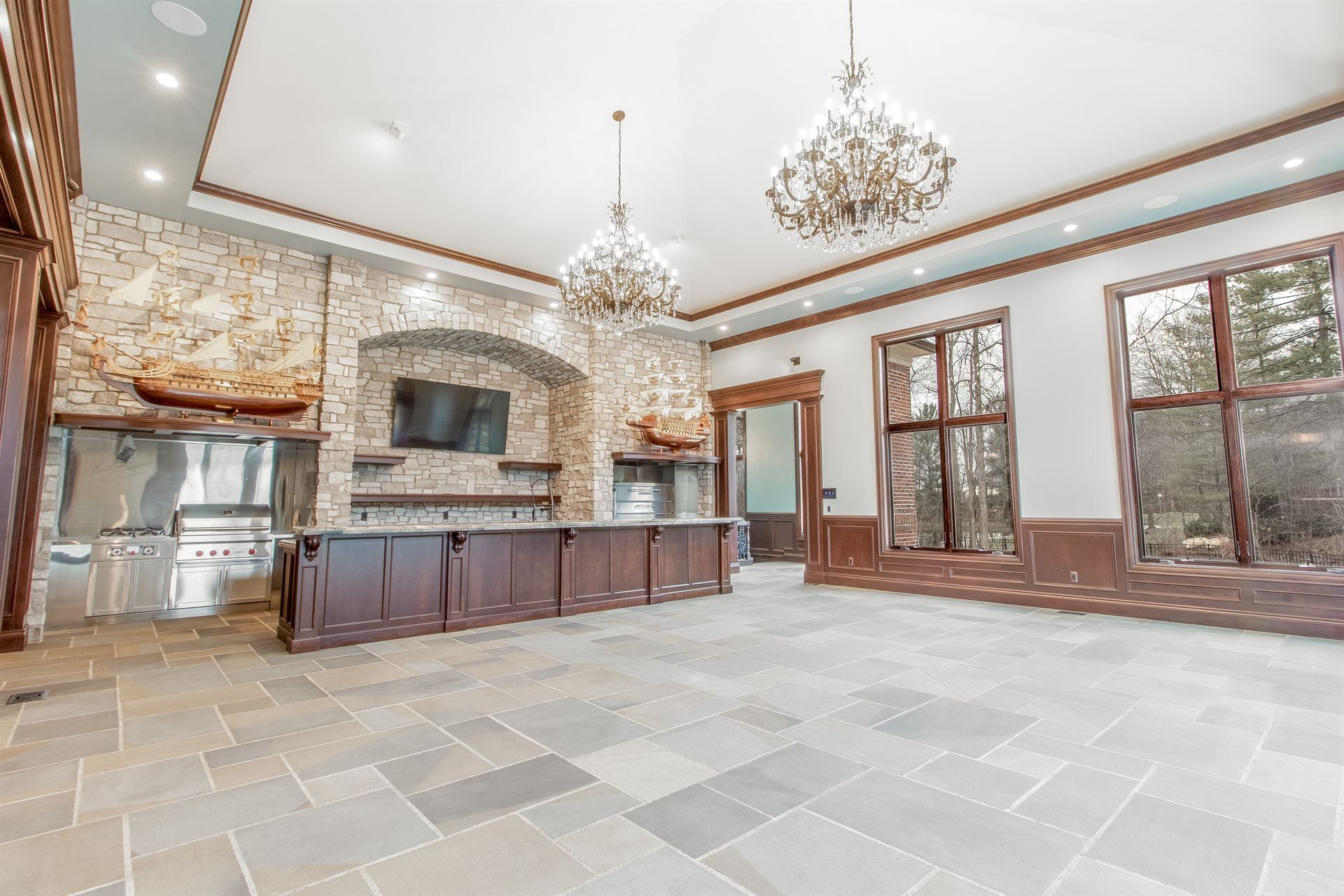 great-room-with-a-stone-fireplace-arch-dark-wood-island-and-chandeliers-southeast-mi-optimized