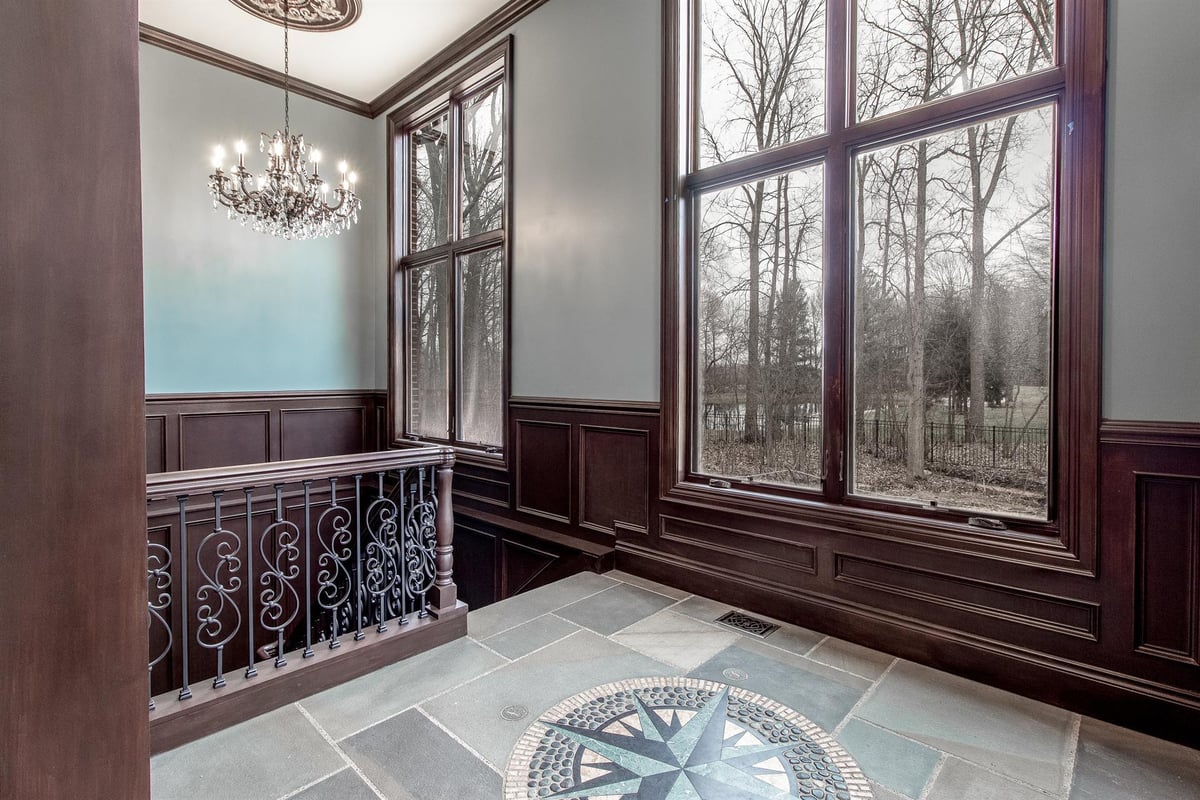 stair-landing-with-dark-wainscoting-iron-railing-and-a-compass-floor-inlay-southeast-mi-optimized