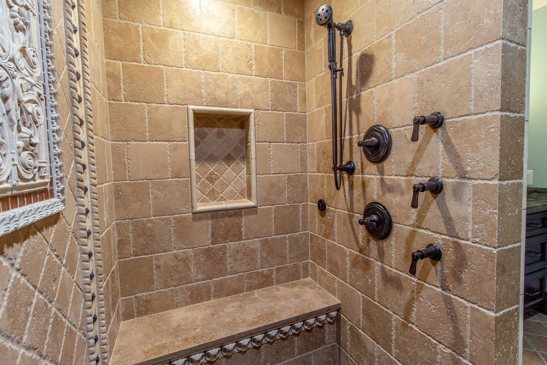 travertine-shower-with-a-carved-panel-body-sprays-and-a-bench-southeast-mi-optimized