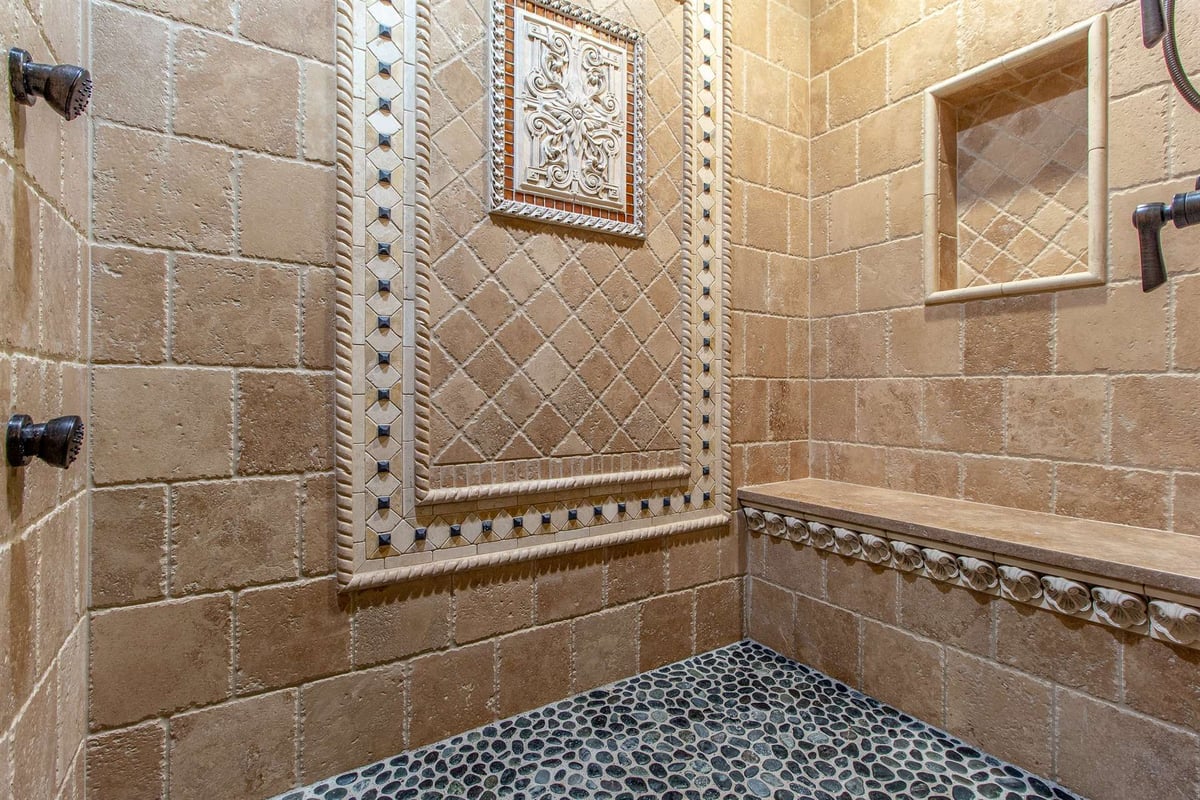 travertine-shower-with-a-medallion-niche-and-pebble-tile-floor-southeast-mi-optimized