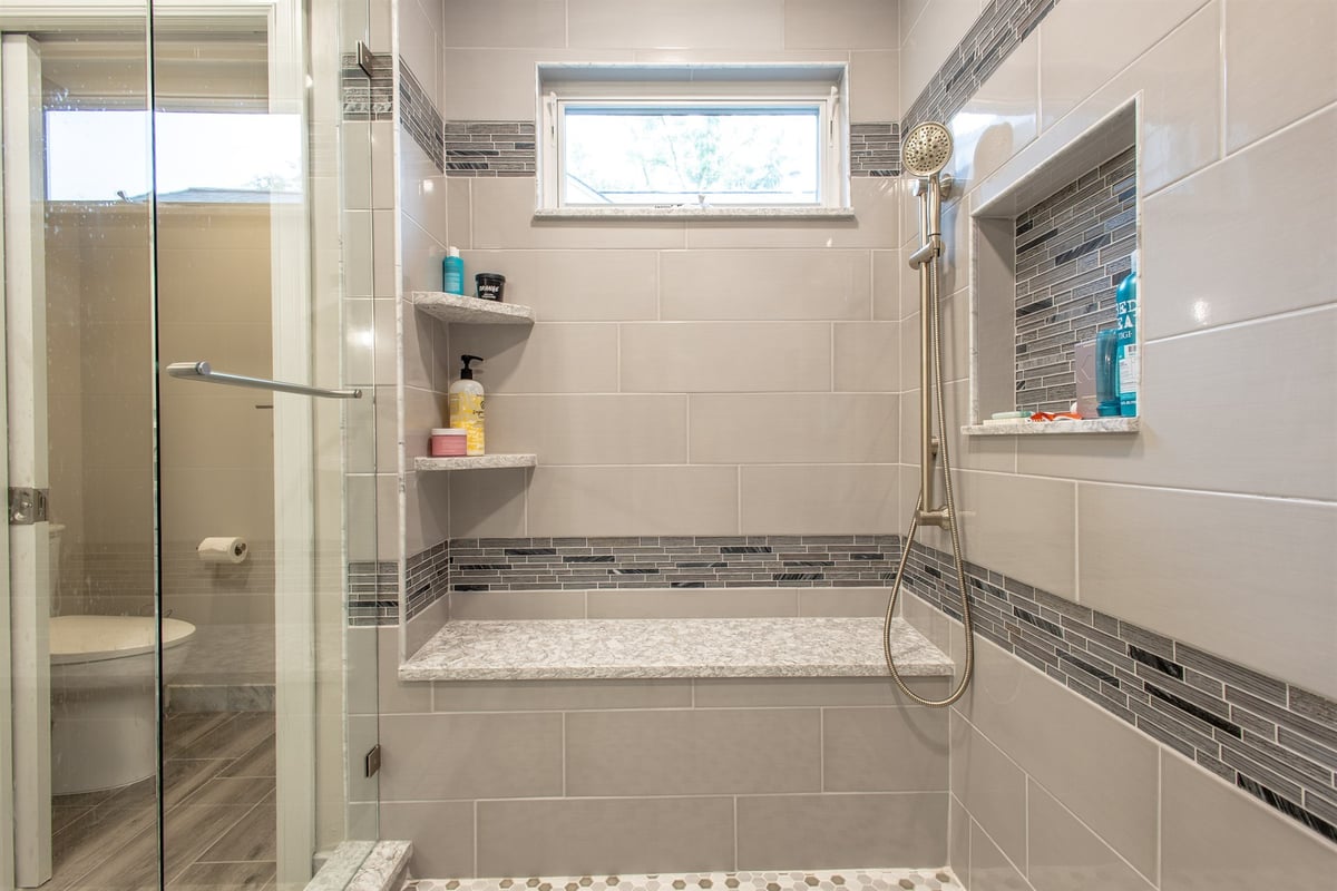 walk-in-shower-with-a-bench-and-window-beside-a-private-water-closet-southeast-mi-optimized