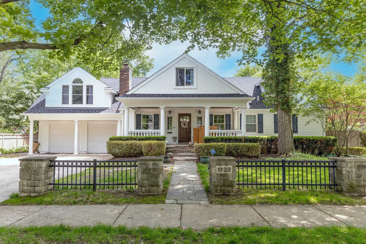 front-of-a-white-home-with-a-covered-porch-dormers-and-stone-fence-southeast-mi-optimized