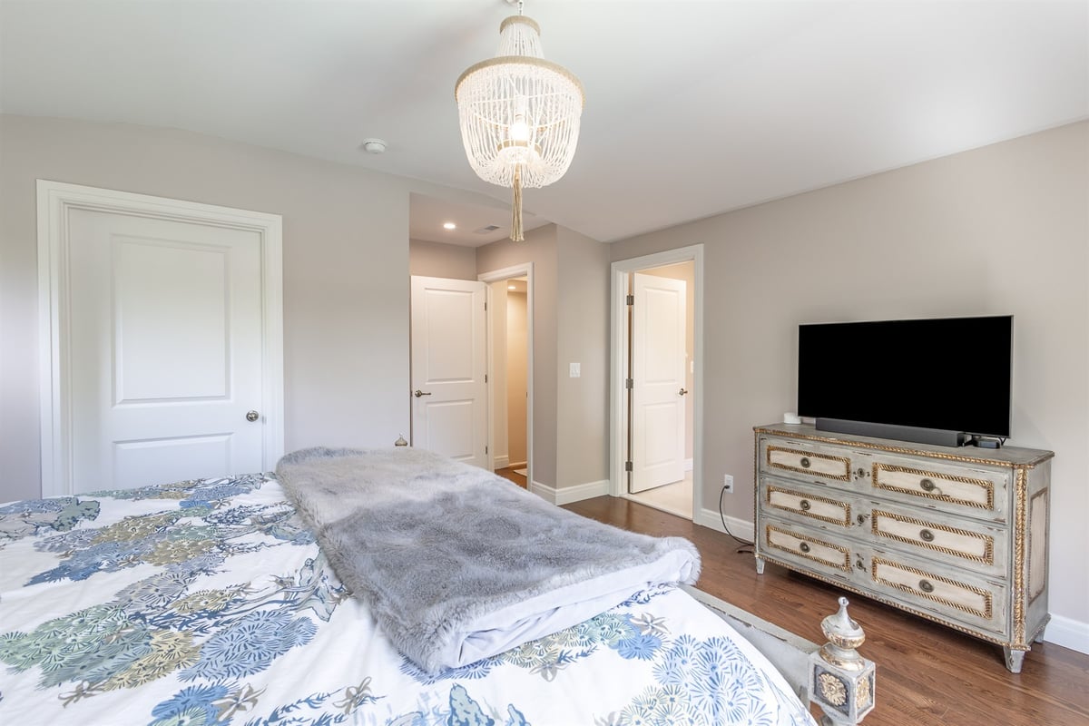 master-bedroom-with-a-beaded-chandelier-dresser-and-hardwood-floors-southeast-mi-optimized