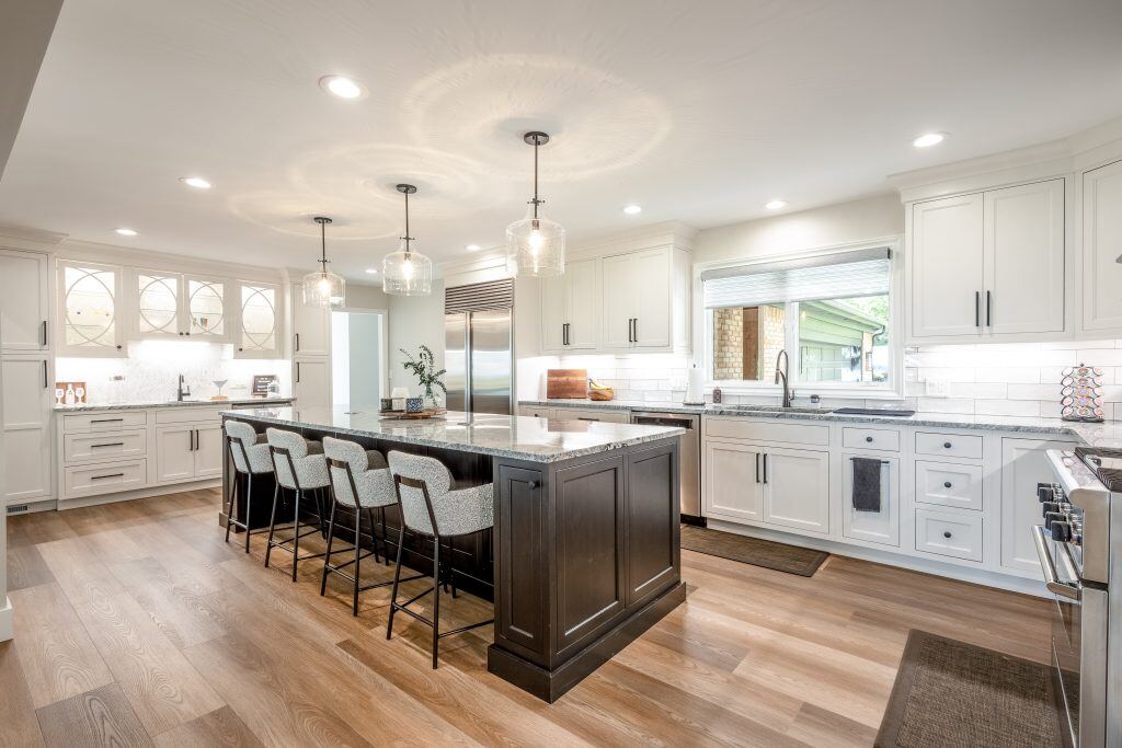 large kitchen remodel in Michigan with wooden floors, white cabinets, and large custom kitchen island with bar stool seating
